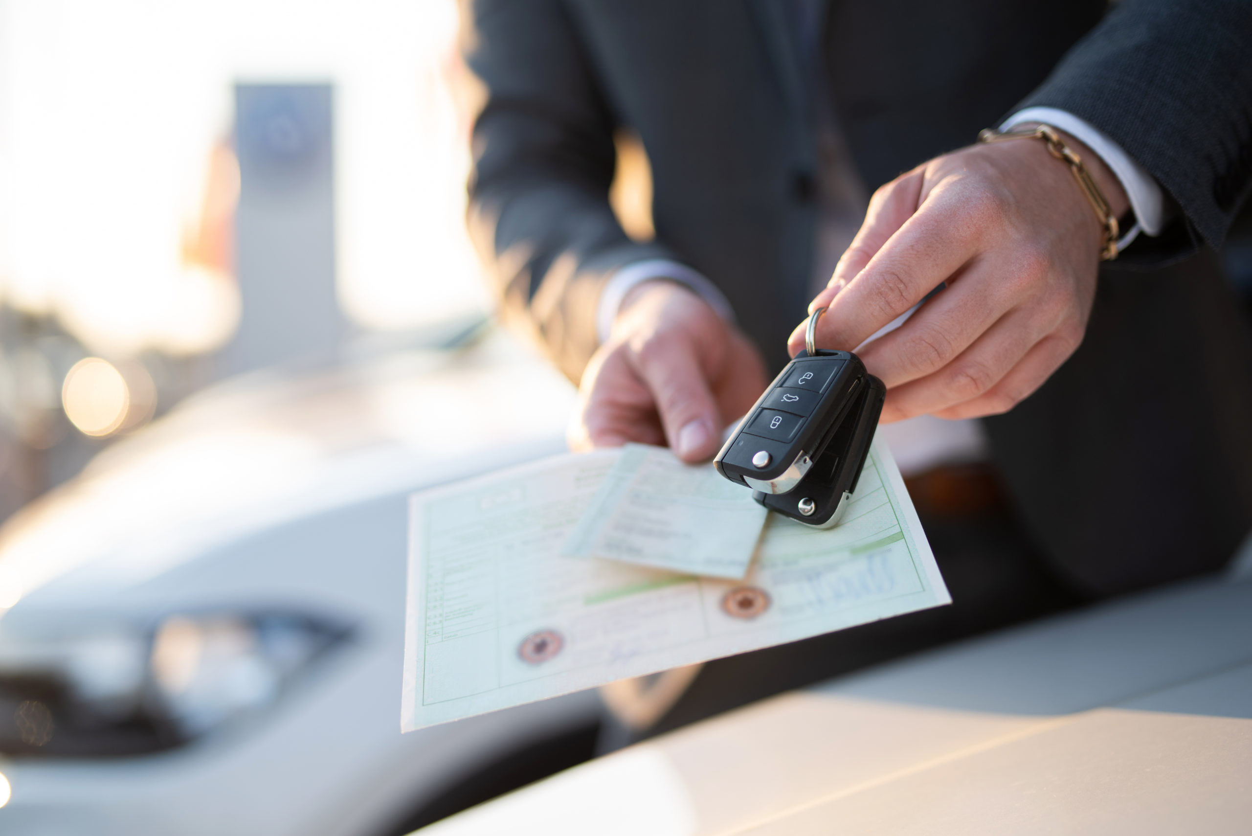 business man holding keys to a car along with paperwork